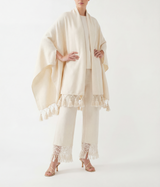 Woman wearing a ecru shawl with tassels details on a white background