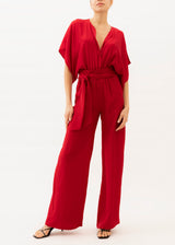The model is wearing a Red silk jumpsuit with belt