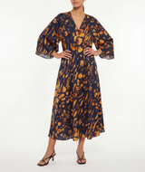 Woman wearing a navy and gold patterned dress on a white background