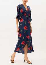 The model is wearing a Navy blue maxi dress with red flowers print