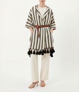 Person wearing a striped shawl with tassels and a belt on a white background