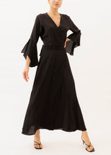 The model is wearing a black flowy maxi dress with v-neck and long sleeves