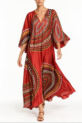 Woman wearing a maxi scarf cut 3/4 sleeve kaftan in a rust crimson print. 