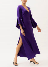 The model is wearing a purple silk maxi dress