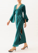 The model is wearing a teal silk maxi dress