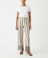 Woman wearing a white top and striped pants with fringe on a white background