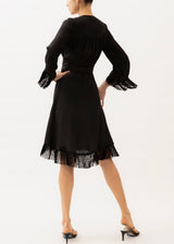 black wrap dress with fringe on the hemline and sleeves