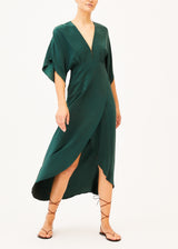 The model is wearing a green silk maxi dress