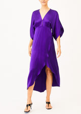 The model is wearing a silk purple maxi dress