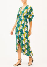 The model is wearing a backless green patterned maxi dress