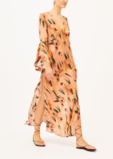 The model is wearing a light pink printed maxi dress on a white background