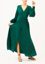 The model is wearing a green wrap maxi dress with long sleeves and a V-neckline,