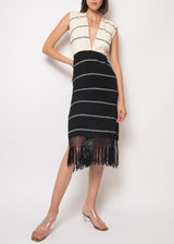 The model is wearing a black and ecru v neck handloomed sheath dress